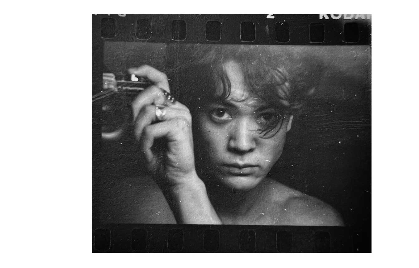 Michael Baastrup Chang, self-portrait photographed in a mirror at Hyelm Hostel in Hampstead, London, 1993